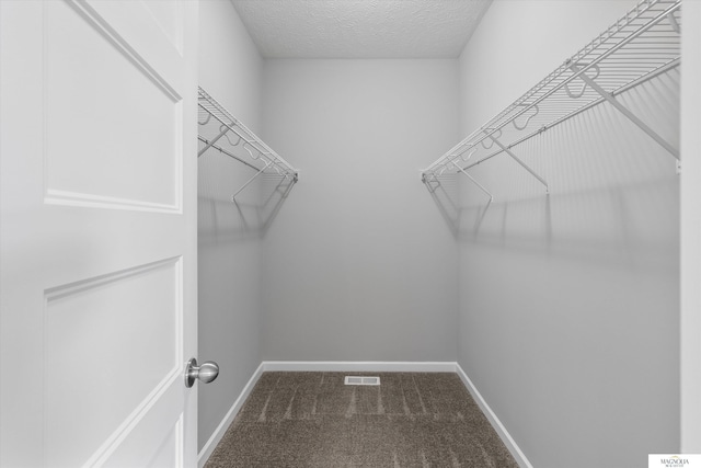 walk in closet featuring visible vents and dark carpet