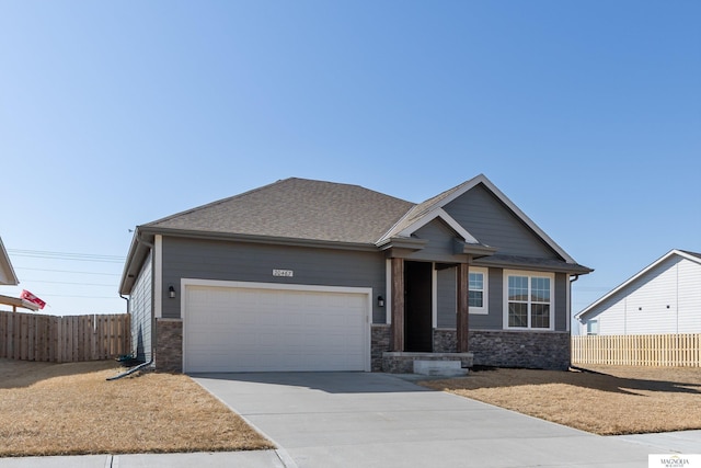 craftsman-style home featuring a garage, stone siding, driveway, and fence