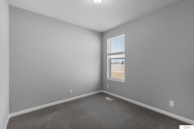 empty room with visible vents, baseboards, and dark carpet