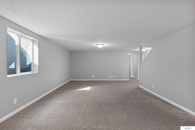 carpeted spare room featuring visible vents, baseboards, and a textured ceiling