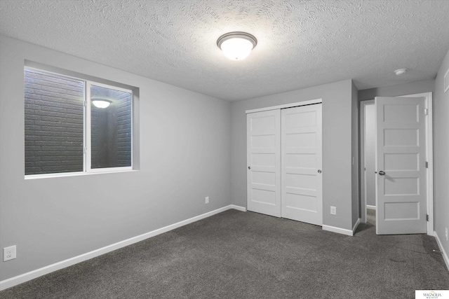 unfurnished bedroom featuring a closet, dark carpet, a textured ceiling, and baseboards