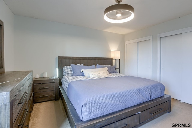 bedroom with light colored carpet and two closets