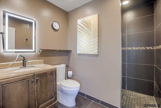 bathroom featuring tile patterned floors, toilet, vanity, and a tile shower