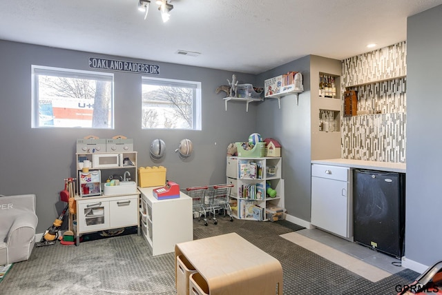 rec room featuring visible vents, a bar, and baseboards