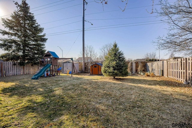 view of yard featuring a storage unit, an outdoor structure, a fenced backyard, and a playground