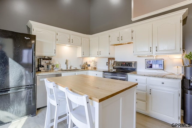 kitchen featuring white cabinets, appliances with stainless steel finishes, butcher block counters, and a sink