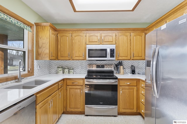 kitchen with tasteful backsplash, stainless steel appliances, light countertops, and a sink