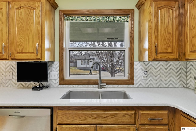 kitchen with tasteful backsplash, dishwasher, light countertops, and a sink