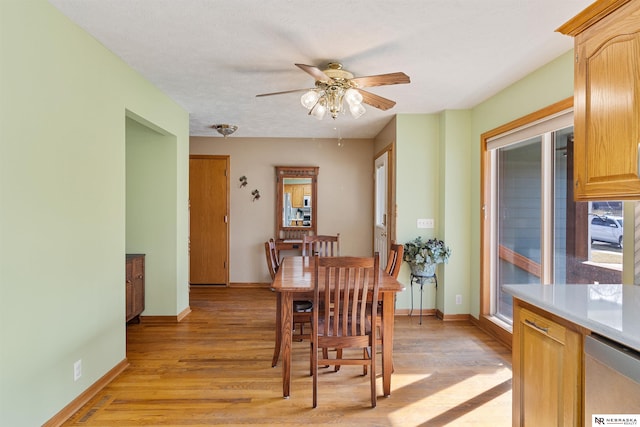 dining area featuring baseboards, light wood-style floors, and a ceiling fan