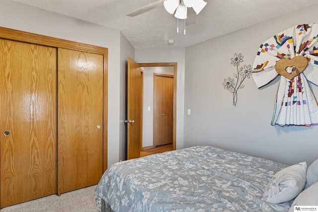 bedroom featuring a closet, a textured ceiling, light carpet, and a ceiling fan