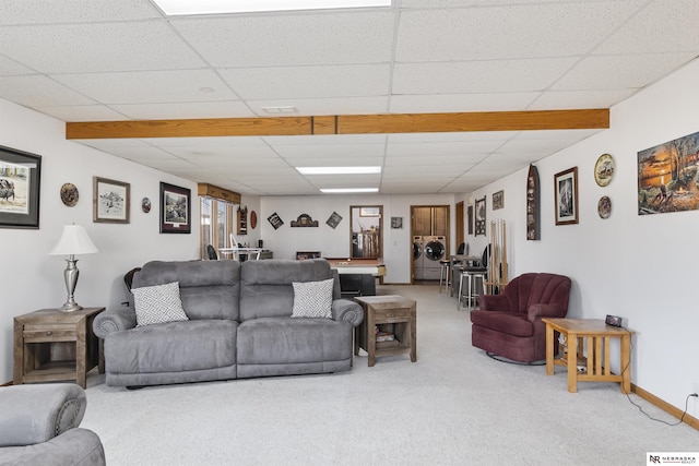 living room featuring a drop ceiling, baseboards, washer / clothes dryer, and carpet