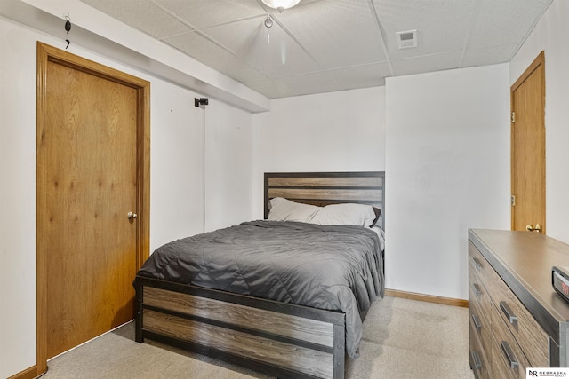 carpeted bedroom with visible vents, a paneled ceiling, and baseboards