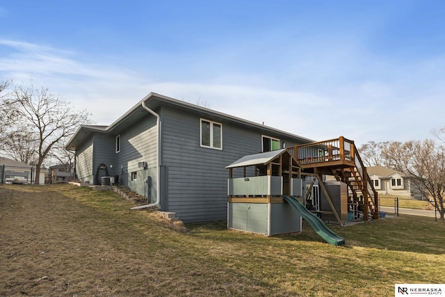 back of house featuring a lawn, stairs, and a playground