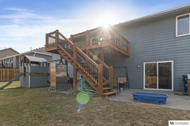 rear view of property featuring a patio, fence, a yard, a hot tub, and a playground