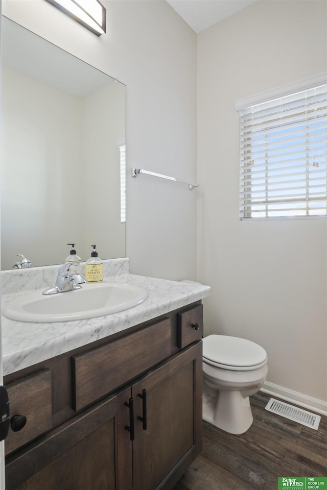 bathroom with visible vents, toilet, wood finished floors, baseboards, and vanity