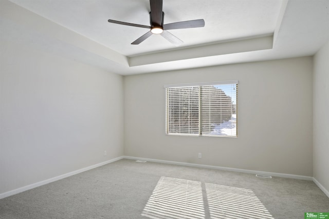 spare room with carpet flooring, visible vents, a ceiling fan, and baseboards