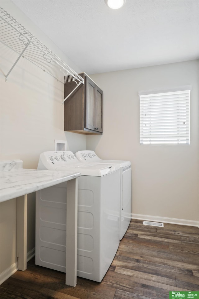 washroom featuring dark wood-style floors, baseboards, visible vents, washing machine and clothes dryer, and cabinet space