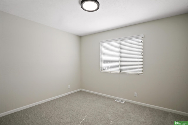 carpeted spare room with visible vents and baseboards