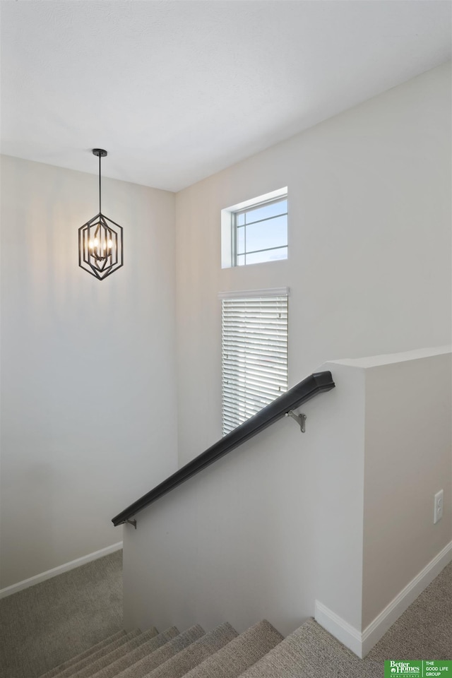 staircase with carpet flooring, baseboards, and an inviting chandelier