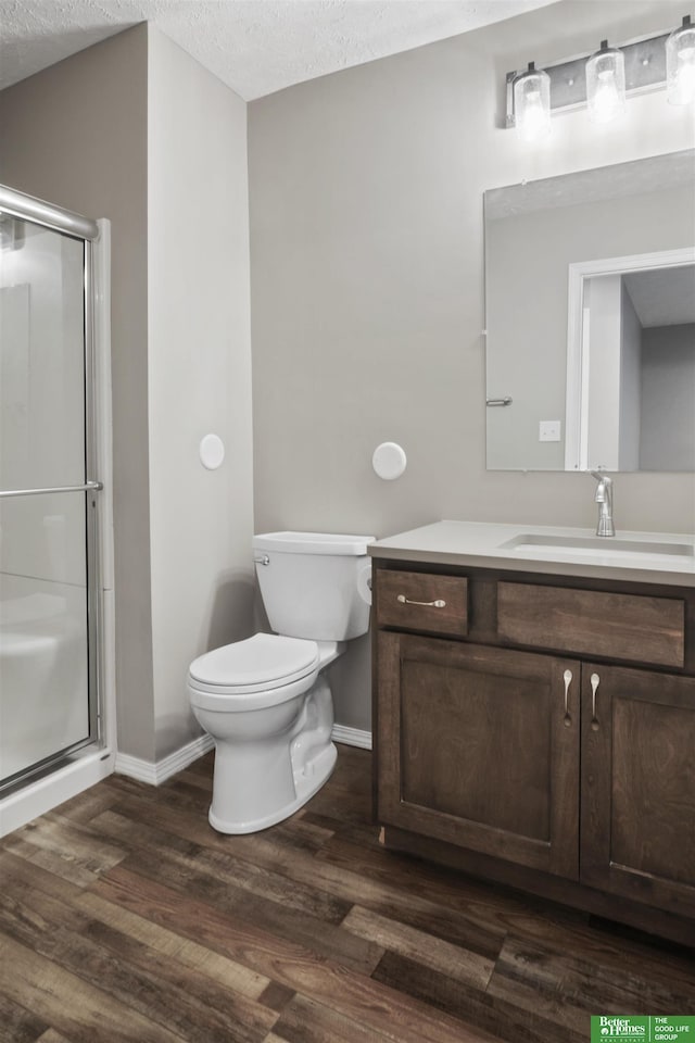 full bath with toilet, a stall shower, wood finished floors, a textured ceiling, and vanity