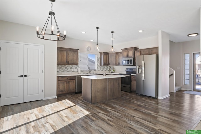 kitchen featuring tasteful backsplash, a kitchen island, dark wood finished floors, stainless steel appliances, and light countertops