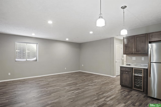 kitchen featuring dark wood-type flooring, freestanding refrigerator, wine cooler, light countertops, and baseboards