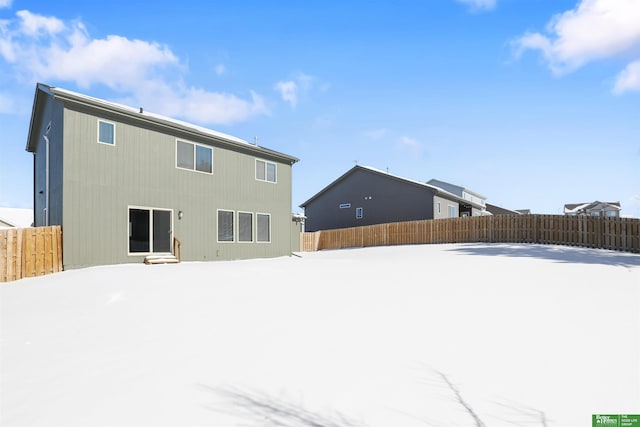 snow covered back of property with a fenced backyard