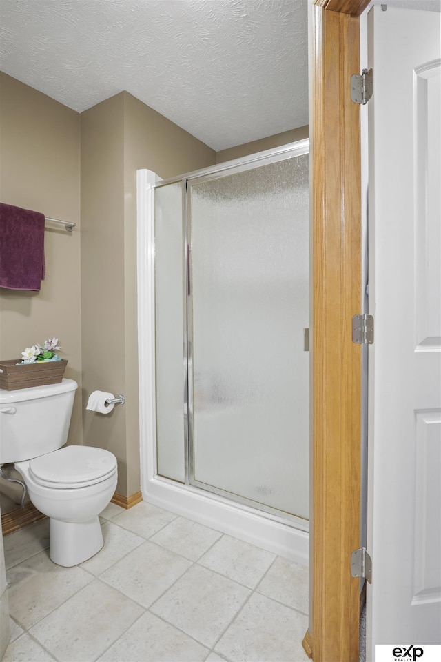 bathroom featuring tile patterned flooring, a shower stall, a textured ceiling, and toilet