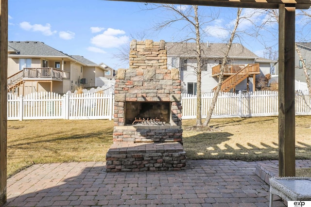 view of patio / terrace featuring an outdoor stone fireplace and a fenced backyard