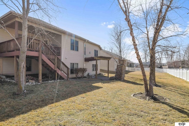 rear view of property with stairway, a lawn, and fence