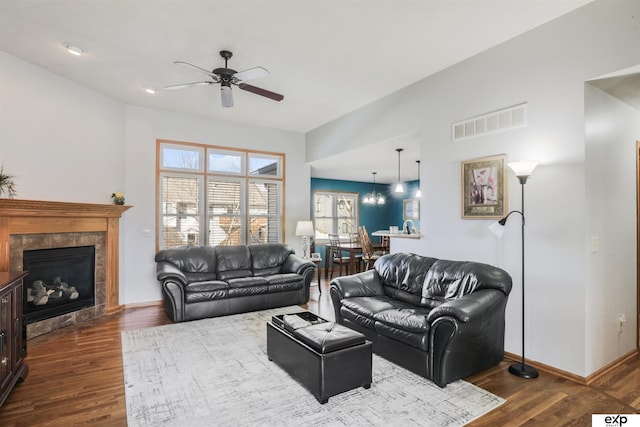 living room featuring visible vents, baseboards, ceiling fan, a tile fireplace, and wood finished floors