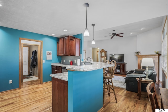 kitchen with a kitchen bar, light wood-style floors, a peninsula, and open floor plan