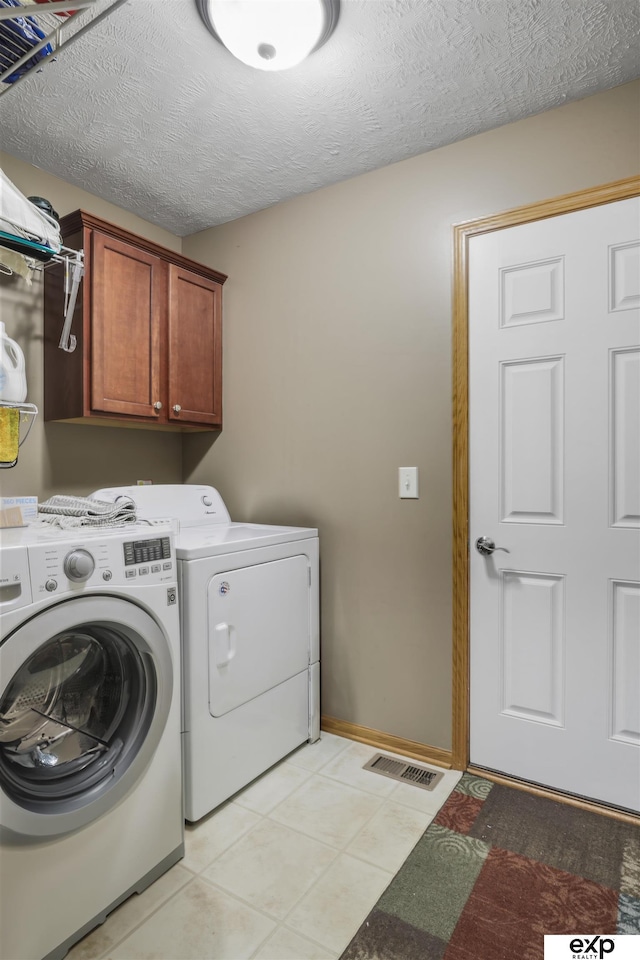 laundry room featuring visible vents, baseboards, washer and clothes dryer, cabinet space, and a textured ceiling