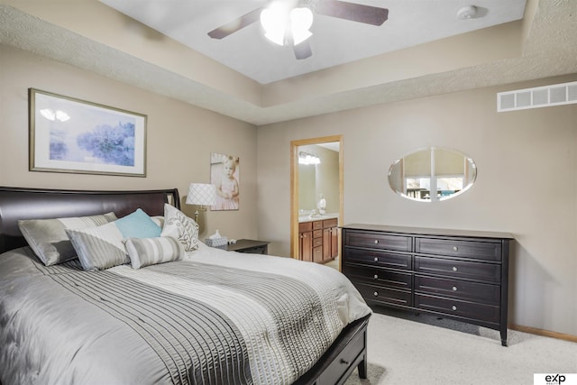 bedroom featuring a ceiling fan, visible vents, baseboards, a tray ceiling, and light colored carpet