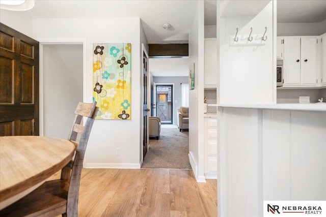 kitchen featuring baseboards, light wood-style floors, white cabinets, and light countertops