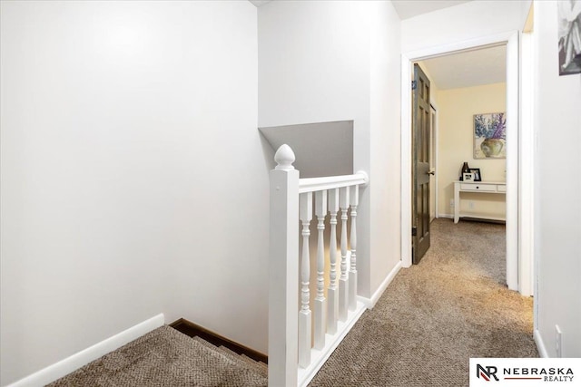 hallway with an upstairs landing, baseboards, and carpet floors