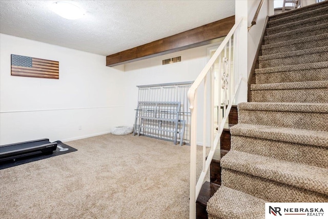 interior space with visible vents, baseboards, a textured ceiling, and carpet flooring