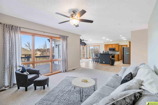 living room with light carpet, light tile patterned floors, a healthy amount of sunlight, and ceiling fan