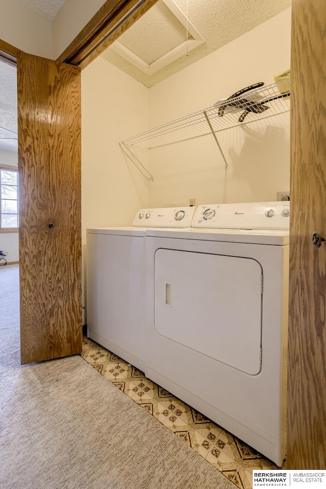 washroom with a textured ceiling, laundry area, light floors, and washing machine and clothes dryer