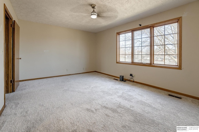 carpeted empty room featuring visible vents, ceiling fan, a textured ceiling, and baseboards