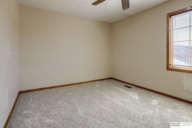 unfurnished room with a ceiling fan, light colored carpet, visible vents, and a textured ceiling