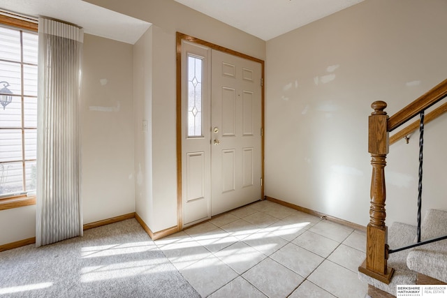 foyer entrance featuring light tile patterned floors, plenty of natural light, and baseboards