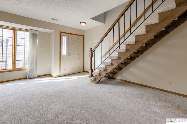 entrance foyer featuring visible vents, baseboards, carpet, stairway, and a textured ceiling