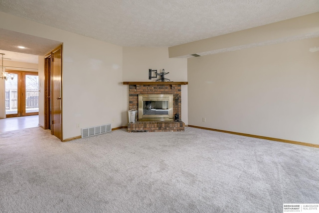 unfurnished living room with baseboards, visible vents, a fireplace, a textured ceiling, and carpet flooring