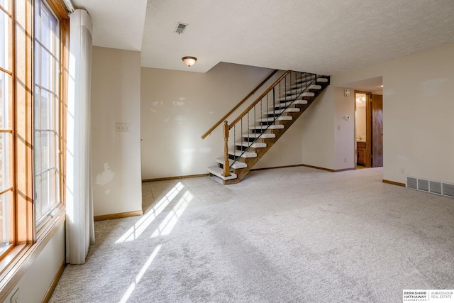 unfurnished living room featuring visible vents, stairs, baseboards, and carpet floors