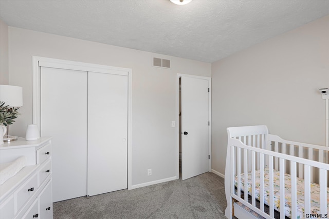 bedroom featuring baseboards, visible vents, a closet, a textured ceiling, and light colored carpet