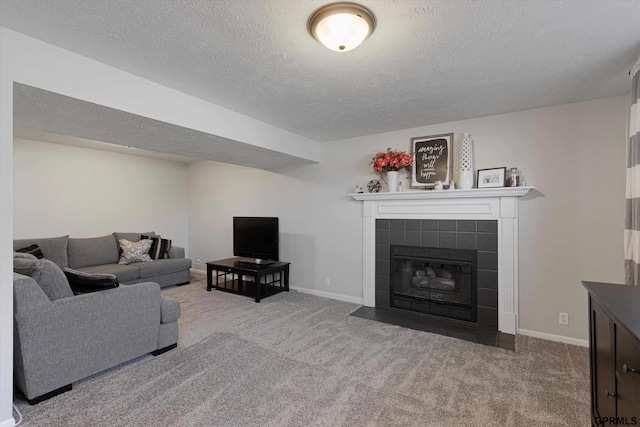 carpeted living room featuring baseboards, a textured ceiling, and a tile fireplace