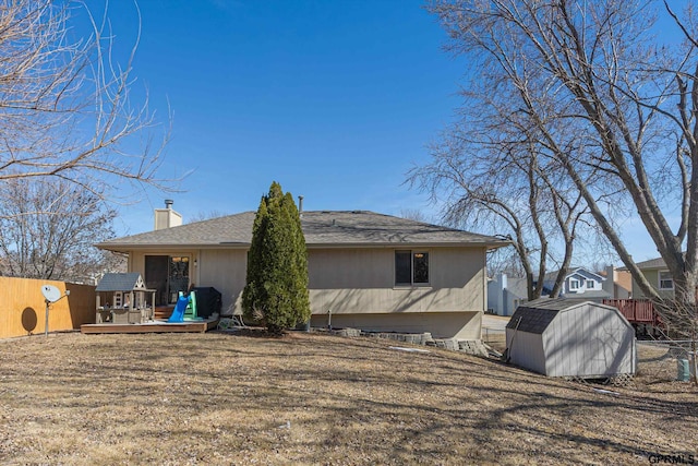 back of property featuring fence, a shed, a chimney, an outdoor structure, and a deck