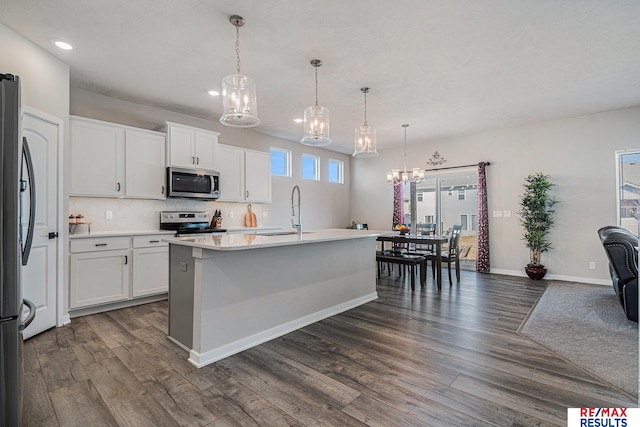 kitchen with a sink, dark wood-type flooring, light countertops, appliances with stainless steel finishes, and a chandelier