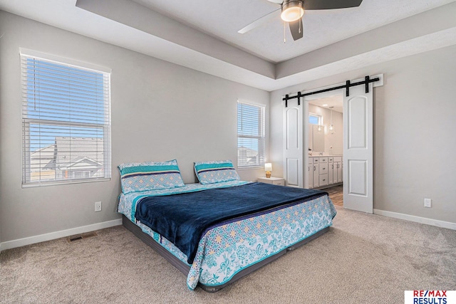 bedroom with visible vents, baseboards, a barn door, a raised ceiling, and carpet flooring